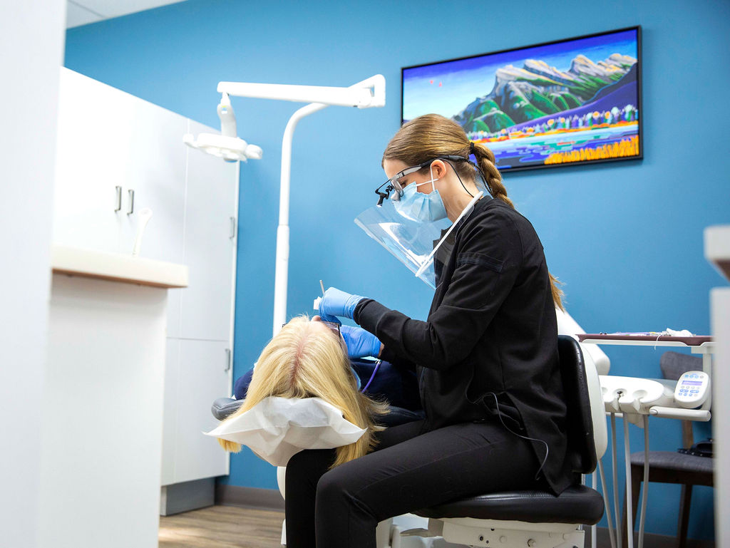 Dental hygienist cleaning a blonde women's teeth