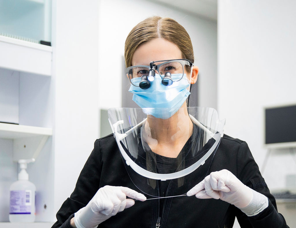 Dental hygienist smiling under her mask, holding a piece of floss