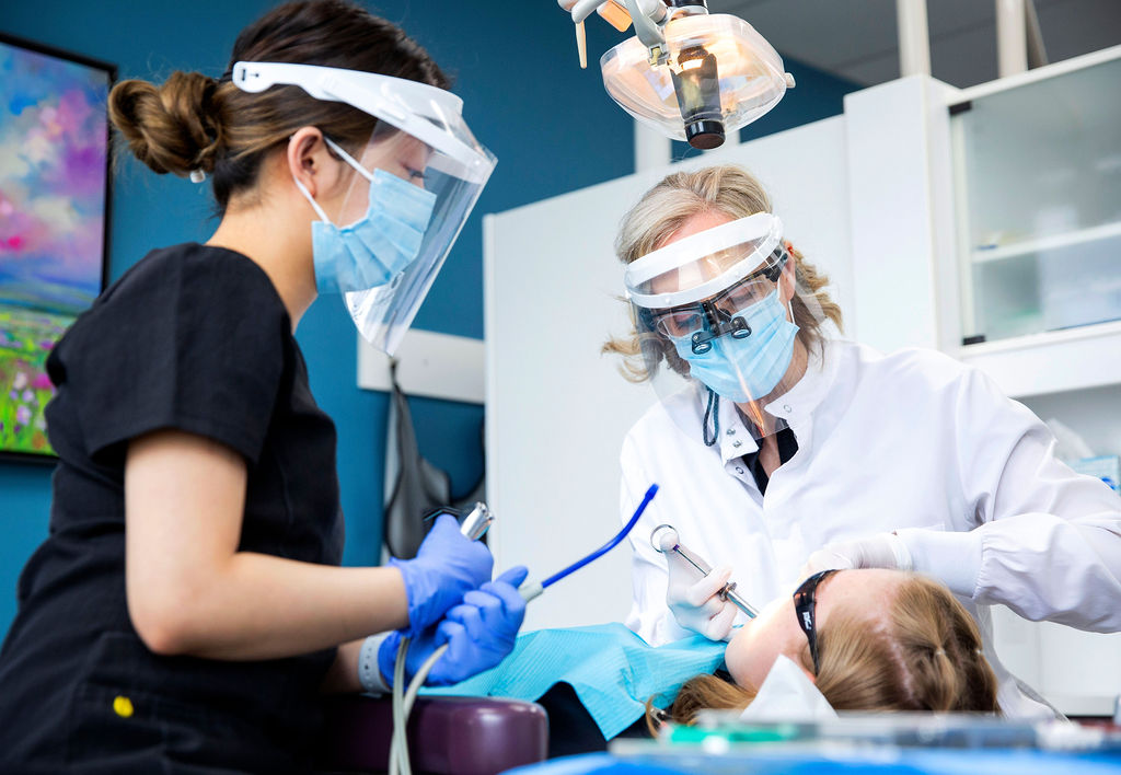 Dentist and dental assistant performing a filling on a young girl